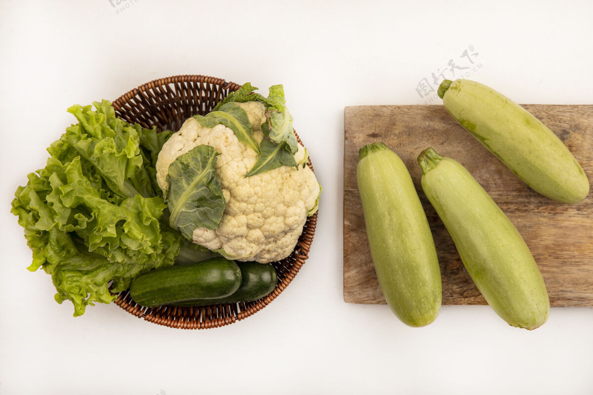 花椰菜新鲜西葫芦的俯视图被隔离在一个木制的厨房板上 白色墙壁上的桶上有菜花生菜和黄瓜生的板叶