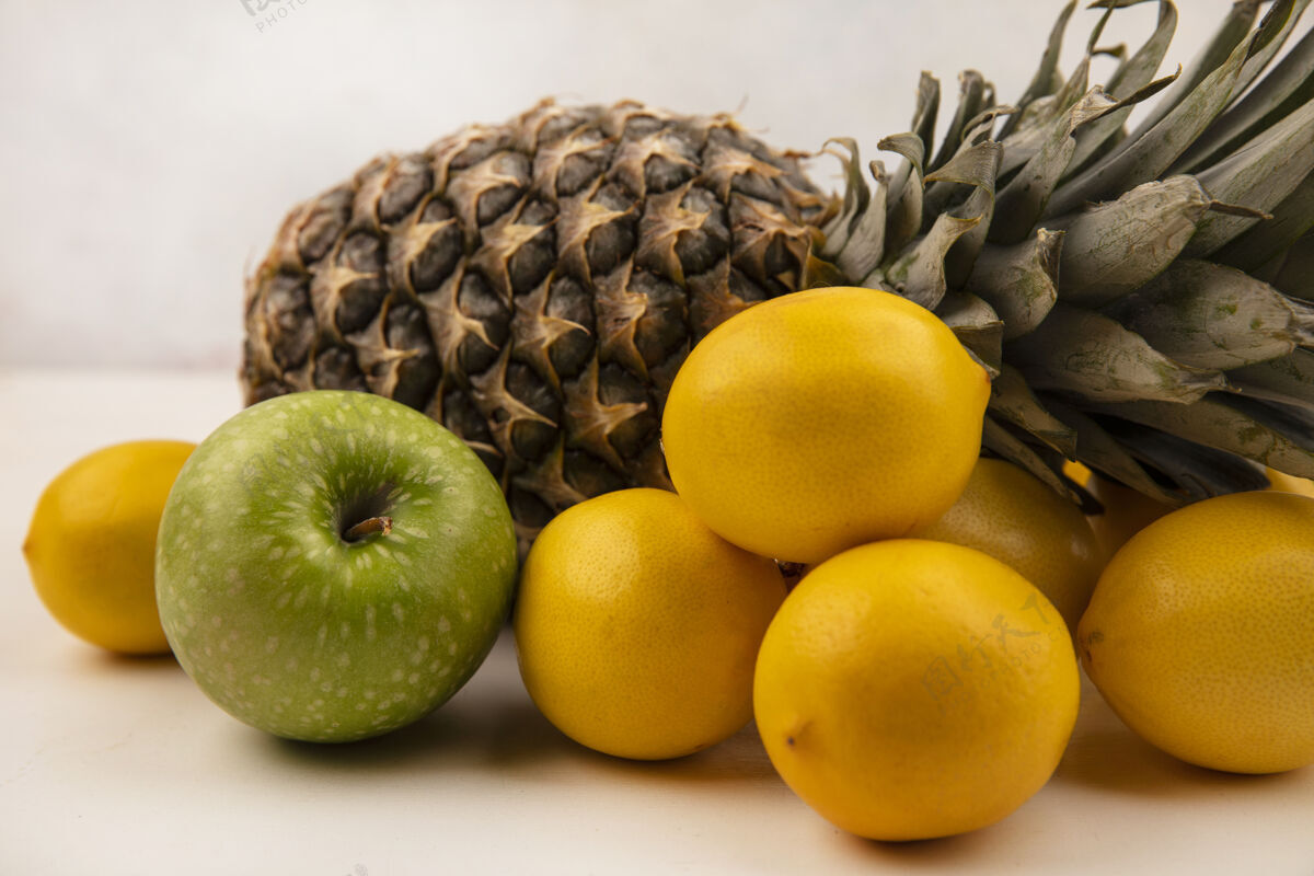 景观侧视图多汁水果 如菠萝绿苹果和柠檬隔离在一个白色的墙壁膳食人多汁