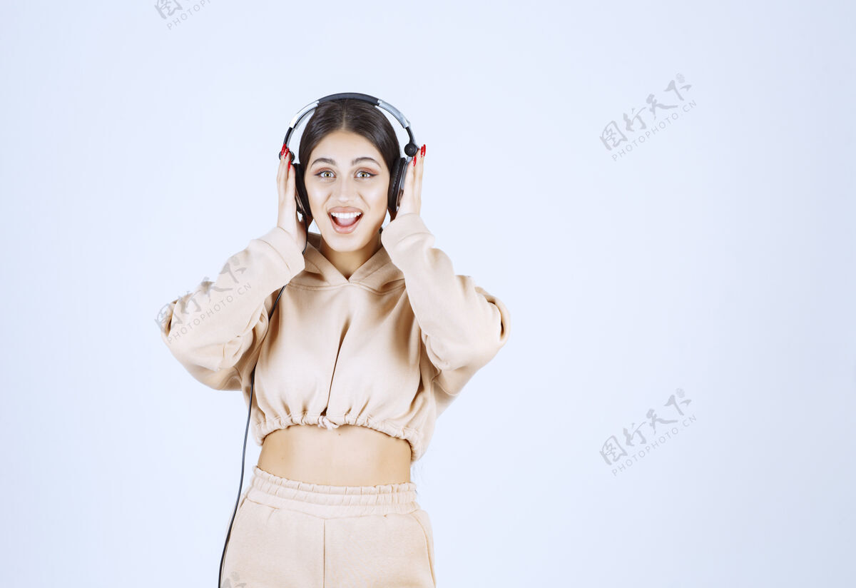 女人年轻女子戴着耳机 愉快地听着她的播放列表乐趣人年轻