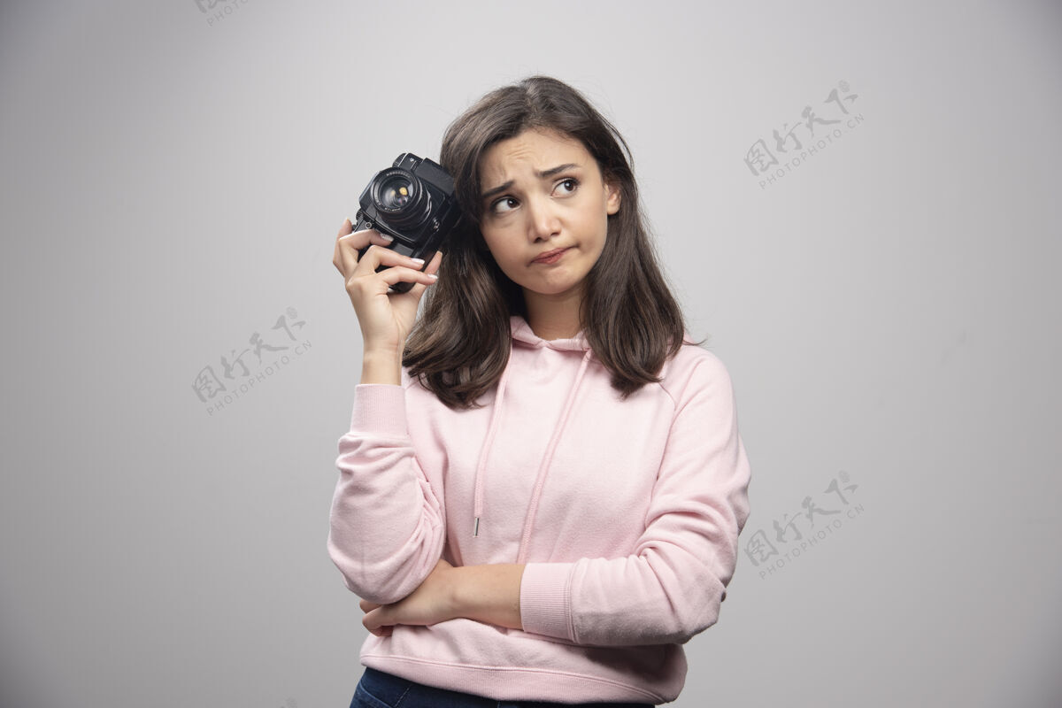 摄影师穿着粉色运动衫拿着相机的疲惫女人年轻可爱女士