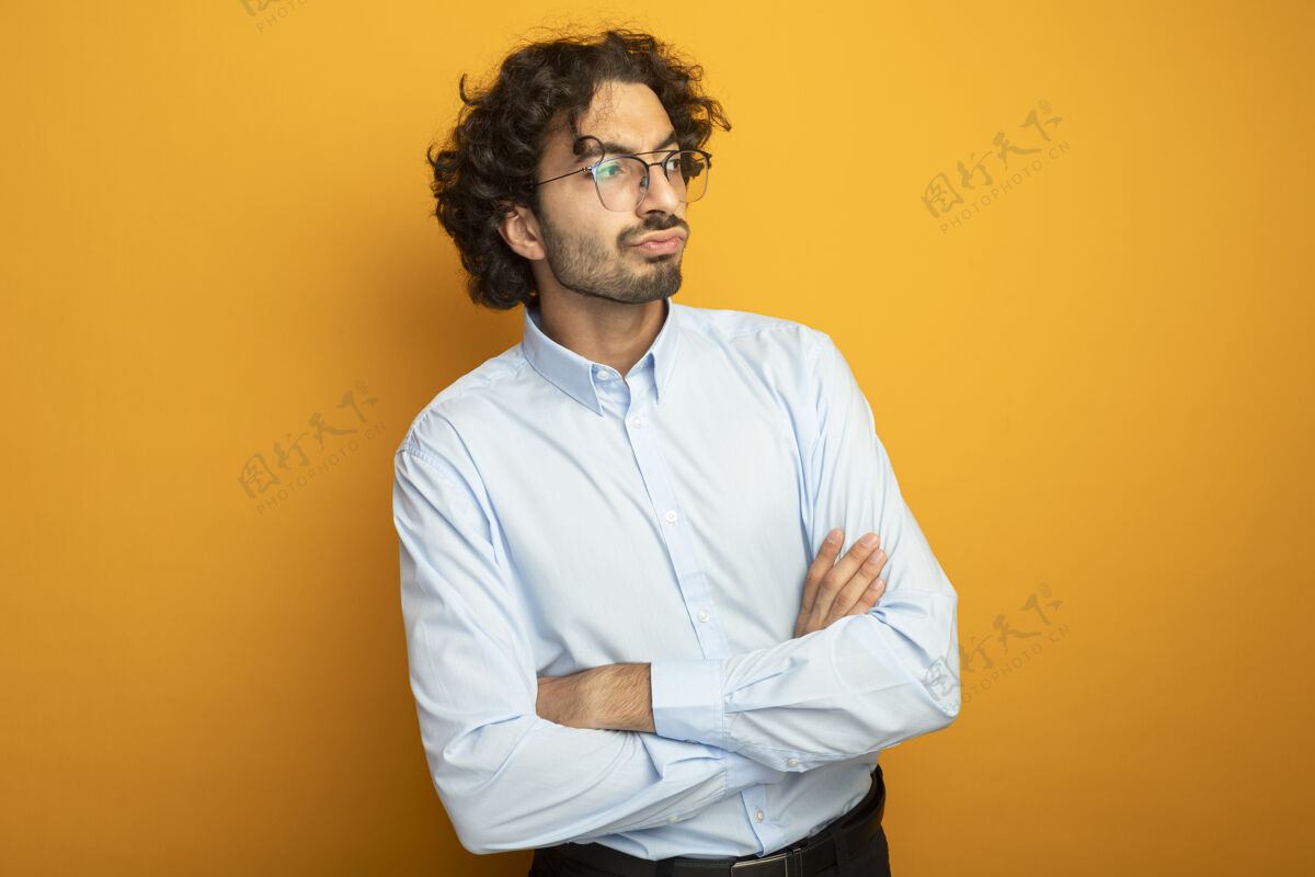 男人年轻英俊的白种人 戴着眼镜 站着 闭着眼睛 看着橙色背景上的一面 留着复印空间姿势橙色壁板