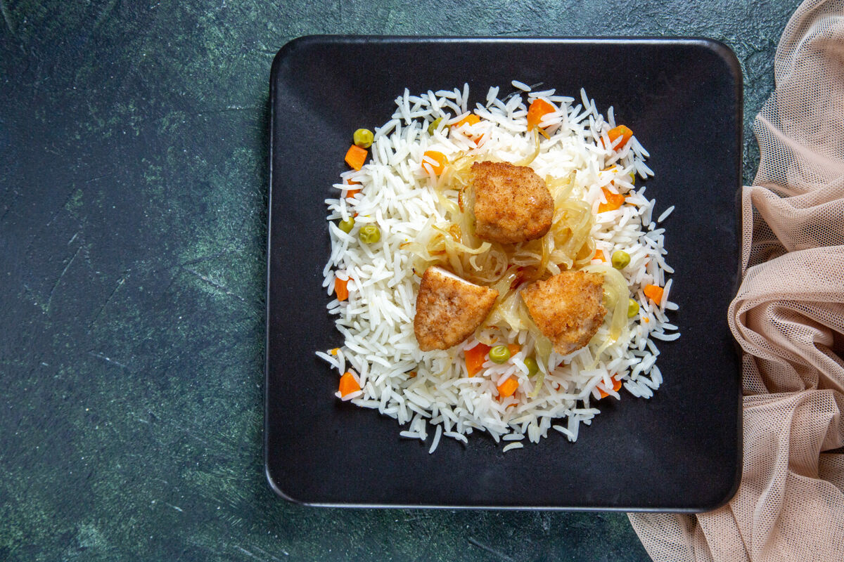 深色在黑暗的桌子上 盘子里放着美味的煮米饭 里面有豆子和肉食物炸鸡正餐