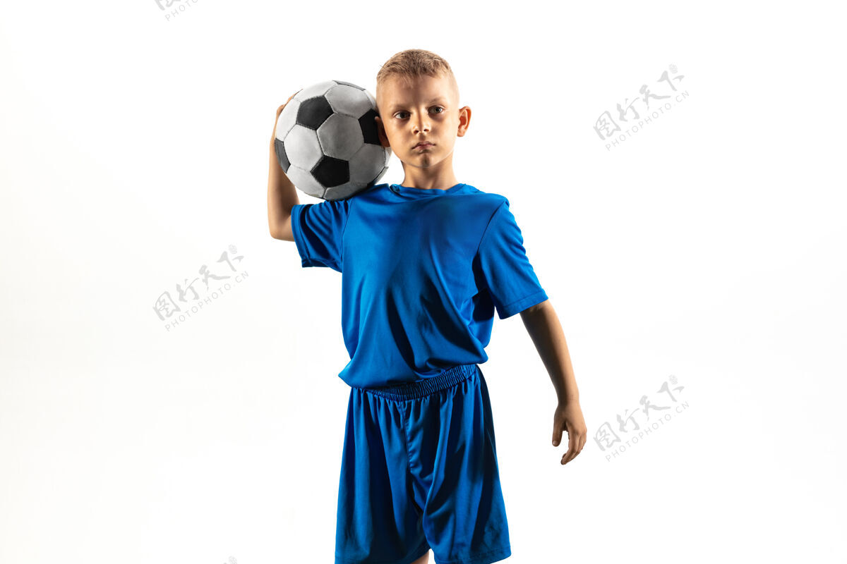 身体一个穿着运动服的小男孩站在足球场上 像个胜利者一样拿着球人活跃体育