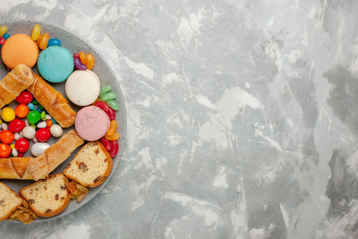 百吉饼白色表面有蛋糕片 麦卡龙和糖果的甜百吉饼俯视图饼干切片食物