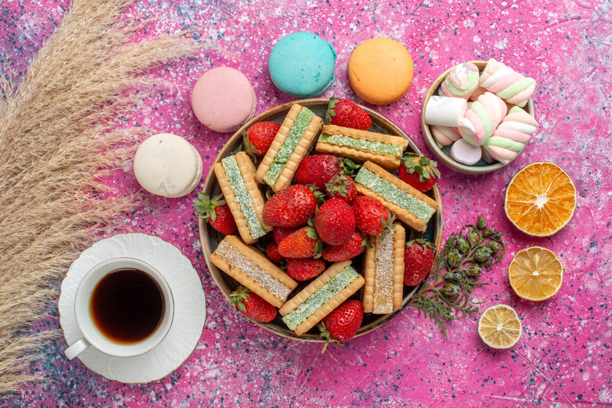 糖美味的华夫饼干的顶视图 新鲜的红色草莓 麦卡龙和粉红色表面的茶水果美味新鲜