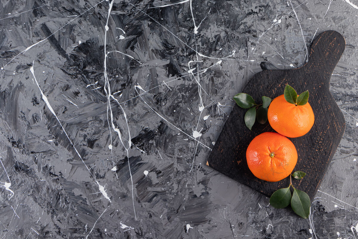 叶子整个新鲜的橙色水果 叶子放在黑色的板上热带橙子甜点
