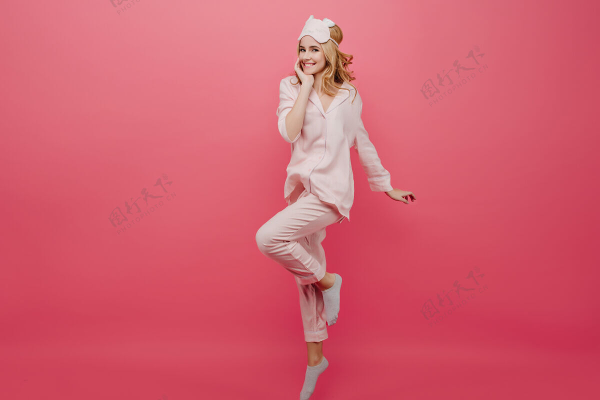 成人穿着睡衣和袜子在粉红色墙上跳舞的迷人女孩的全长肖像戴着眼罩的优雅白人女性在早晨玩得很开心睡衣女人睡衣