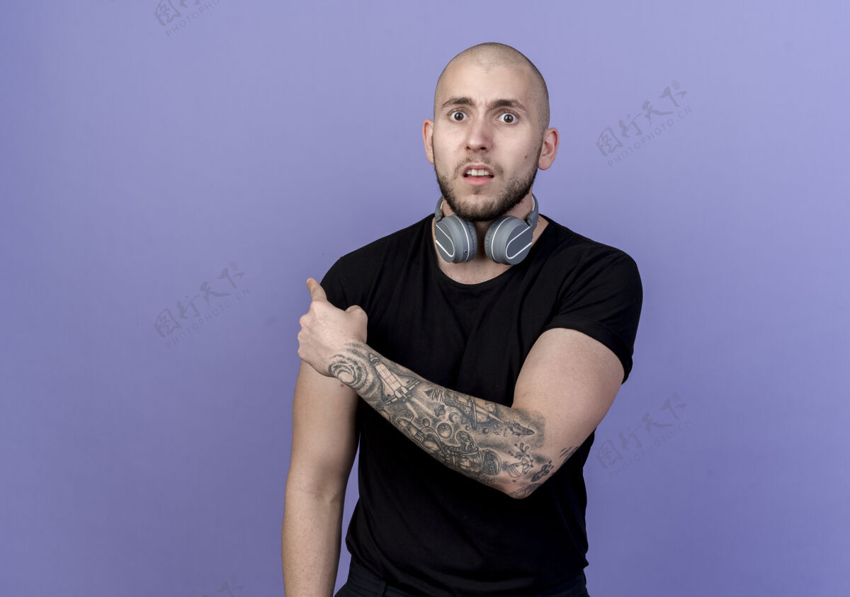男士惊讶的年轻人戴着耳机 脖子上点着紫色的后背佩戴背部运动型