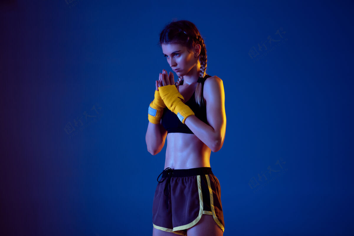 美丽在霓虹灯的蓝色背景下 适合穿运动服拳击的白人女性颜色拳击健康