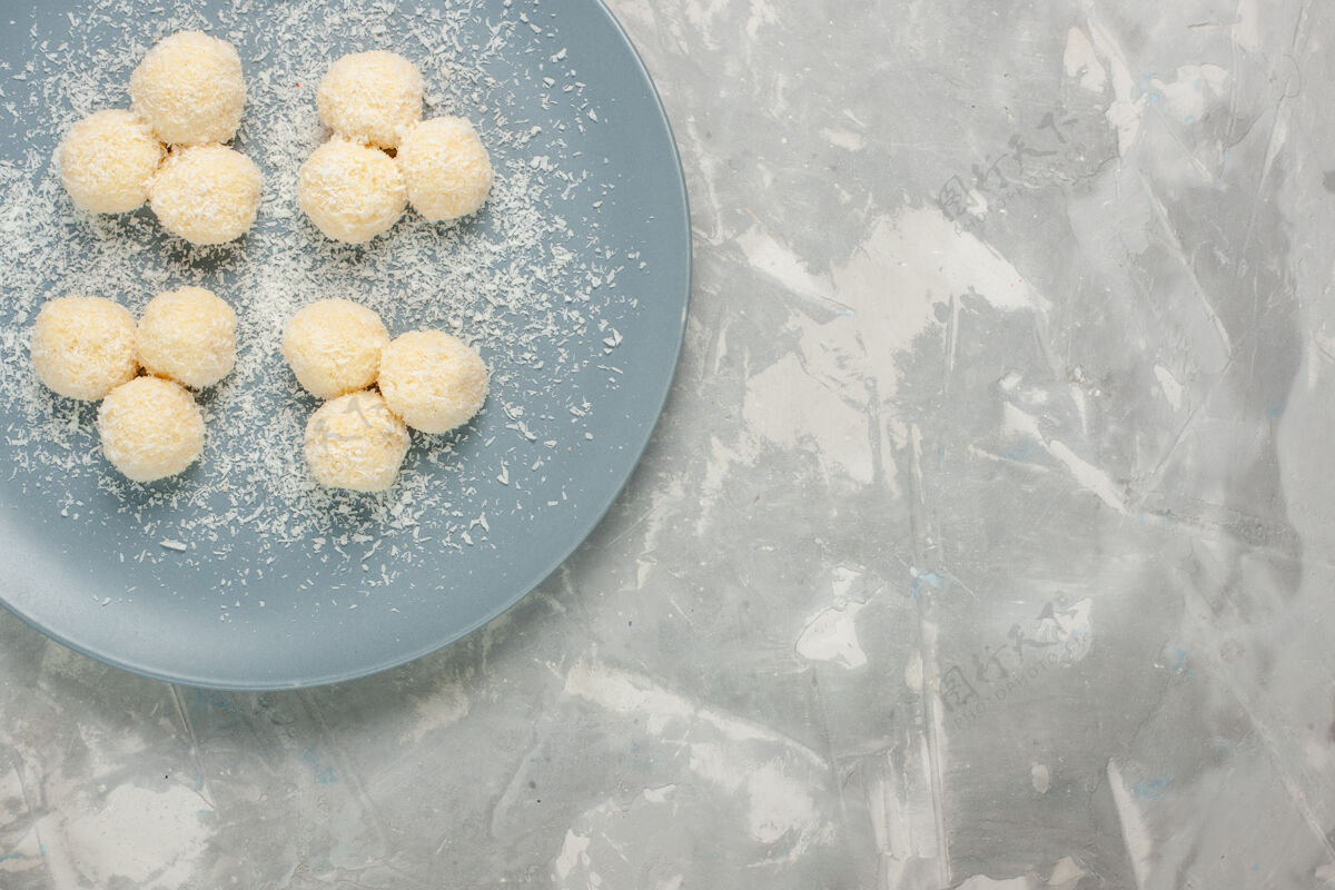 生的白色表面上蓝色盘子内美味椰子糖的俯视图美味水饼干