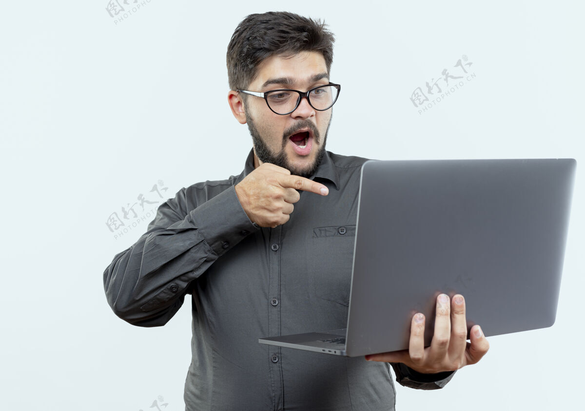 眼镜惊讶的年轻商人戴着眼镜拿着笔记本电脑指着白色的隔离点笔记本电脑男人