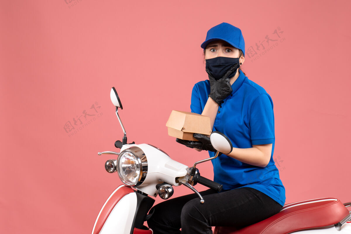 摩托车正面是戴着面具的女快递员 粉红色的小食品包装工人送货自行车