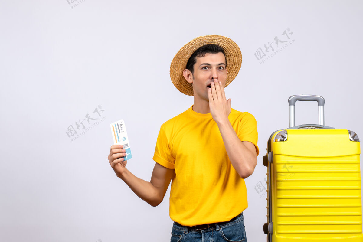 近前视图困惑的年轻游客站在黄色手提箱附近拿着旅行票可爱人抱