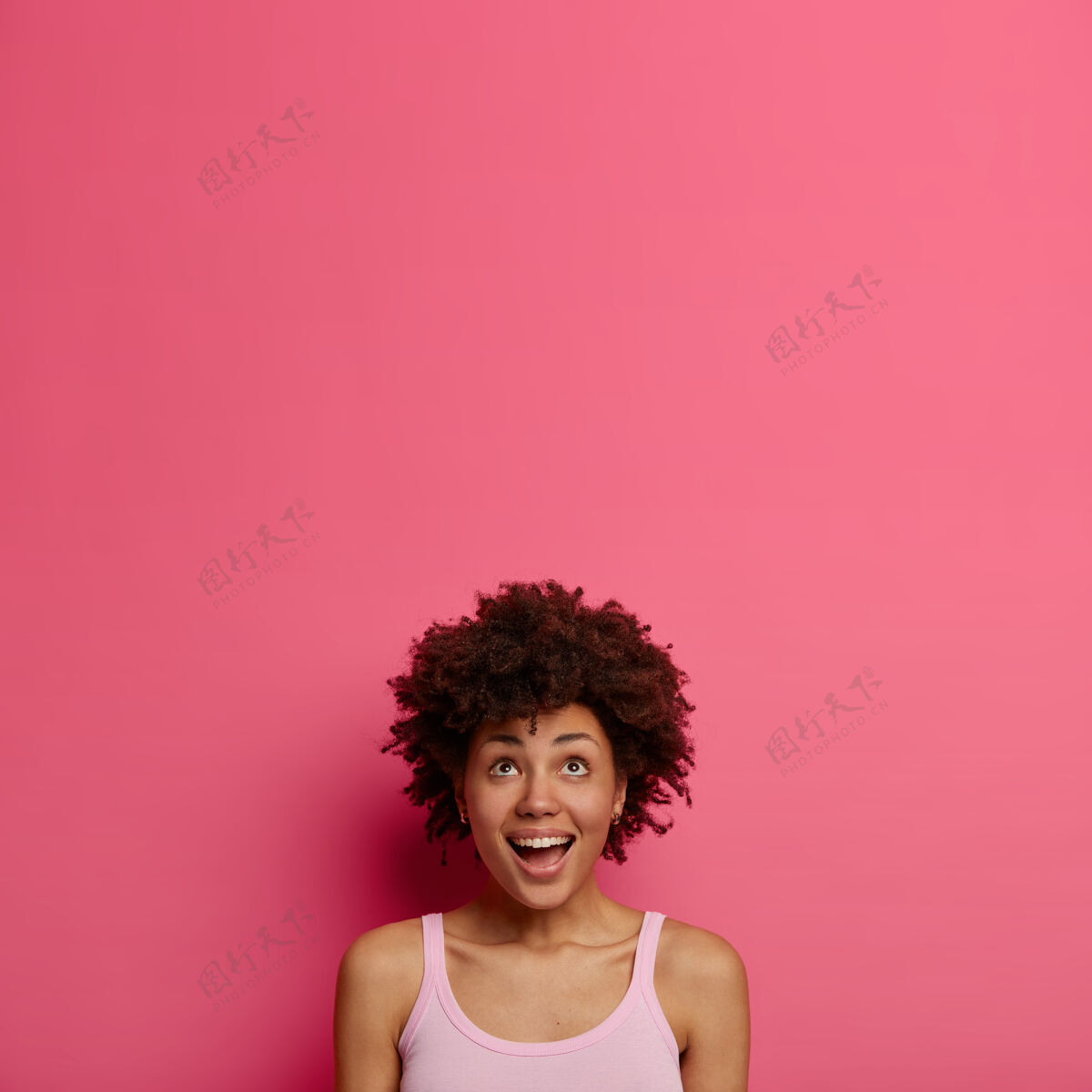 头部快乐好奇兴奋的女人一直向上凝视 带着喜悦的表情抬起头 注意到一些吸引人和有趣的东西 对着粉红色的墙壁摆姿势 为你的文字或推广复制空间种族惊喜美国
