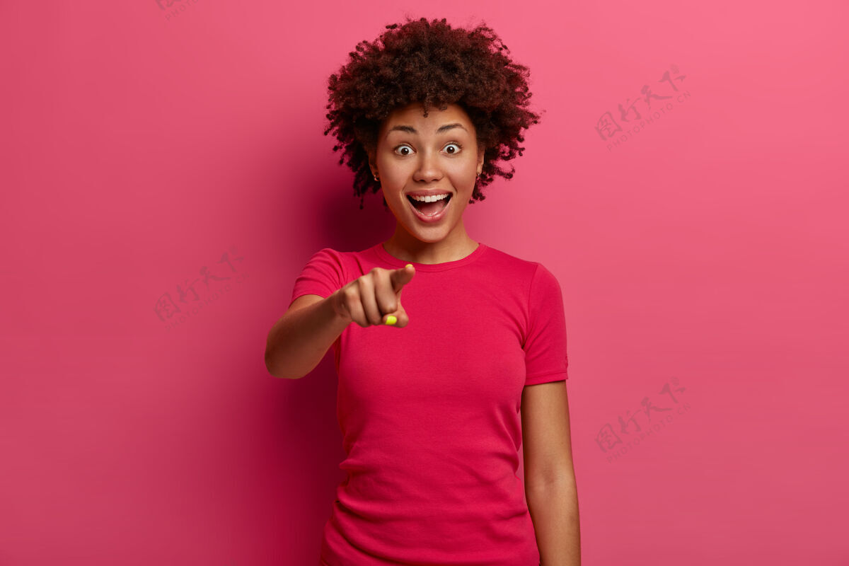 穿开朗的民族女孩用食指指着你 选了一个人 开心地笑了 开心地笑了出来 穿着粉色的t恤 站在深红色的墙上哇 多么神奇的事情非洲积极人