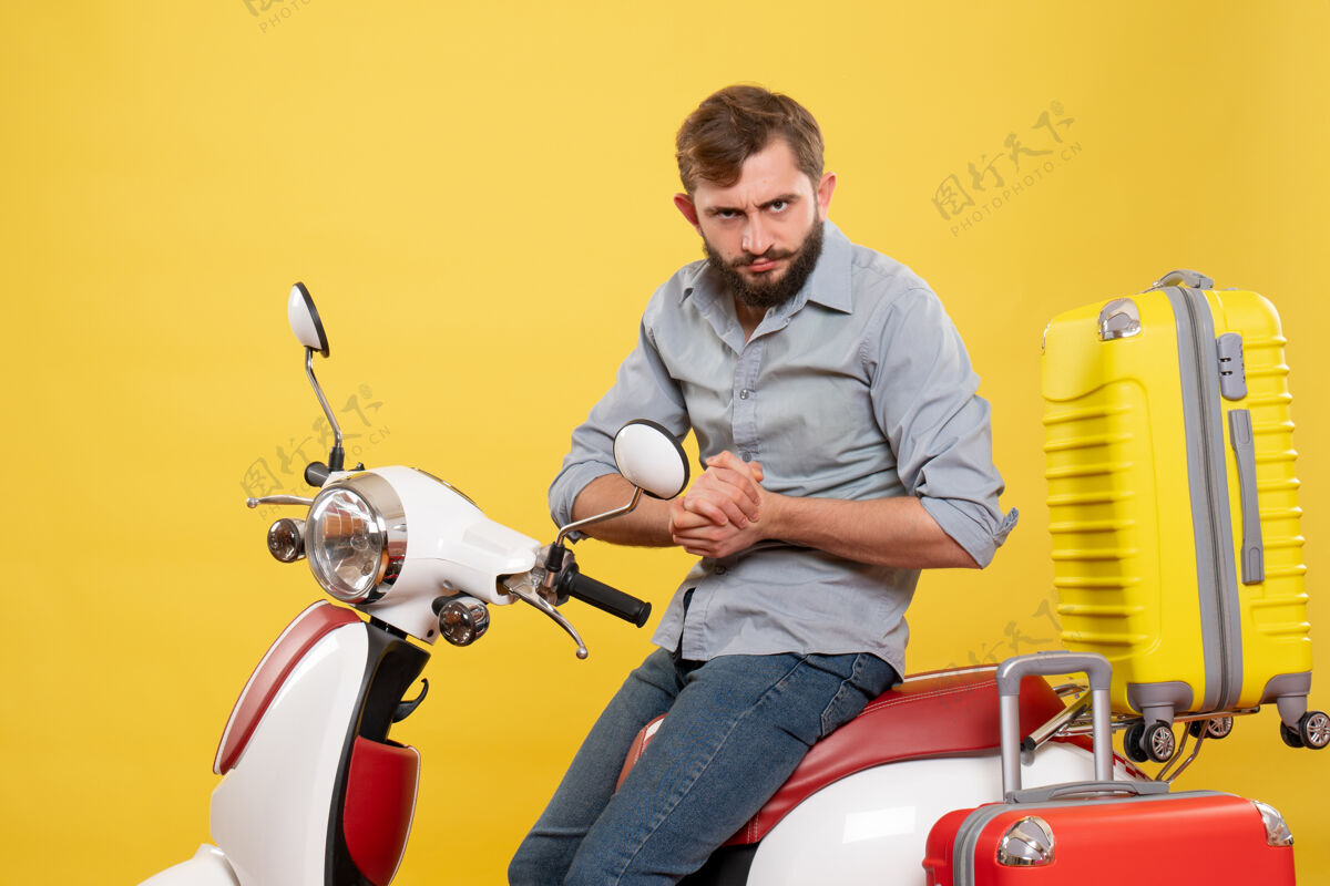 摩托车旅游概念与年轻失望的胡须男子坐在摩托车上它的黄色坐着微笑车辆