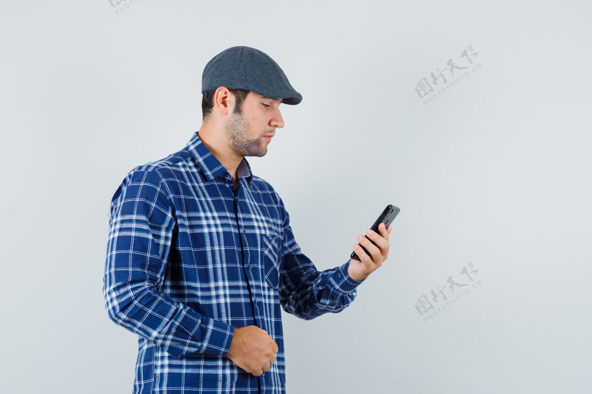聪明年轻人穿着衬衫 戴着帽子 用手机 看上去很忙 前视图朋友休闲年轻