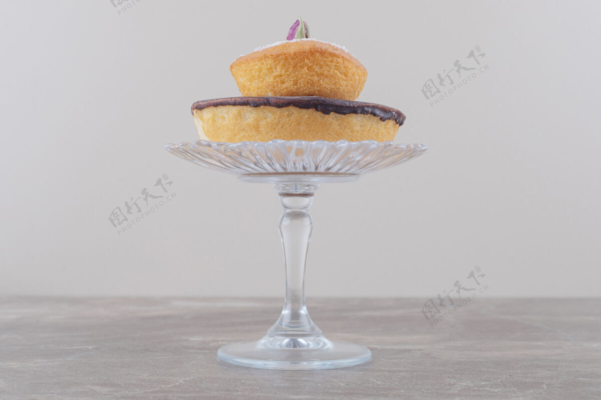顶部巧克力蛋糕和香草粉蛋糕堆在大理石的玻璃基座上糕点烘焙香草