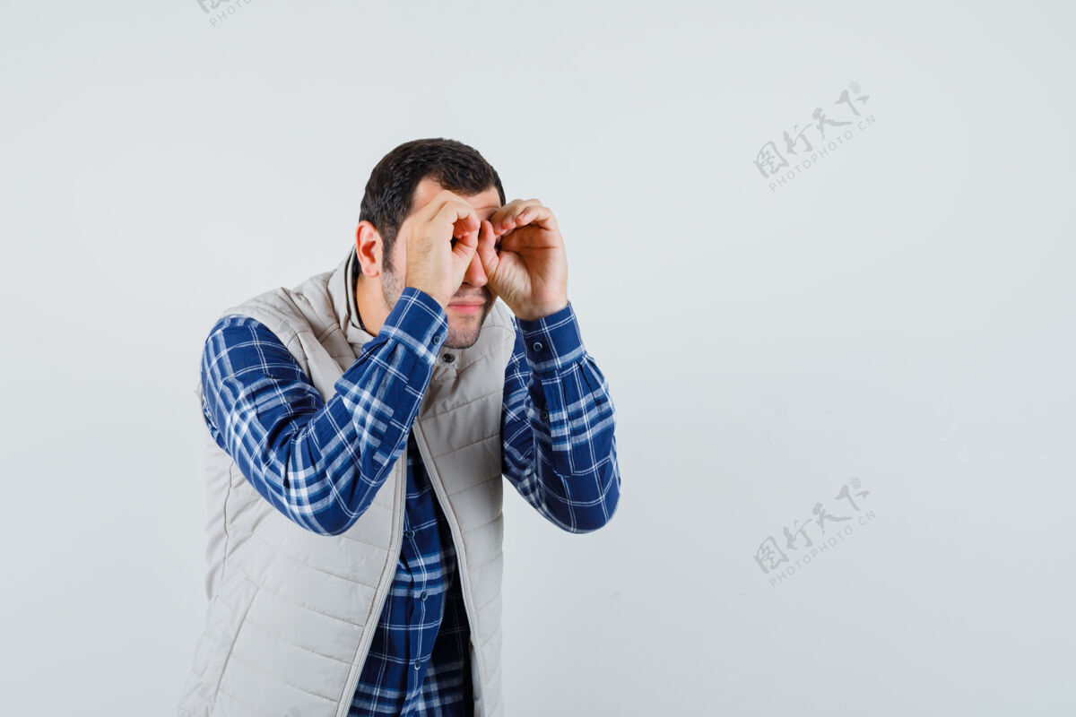 夹克年轻的男性在做望远镜手势 他的眼睛在衬衫 无袖夹克衫和寻找重点 前视图文本空间孩子休闲虚拟