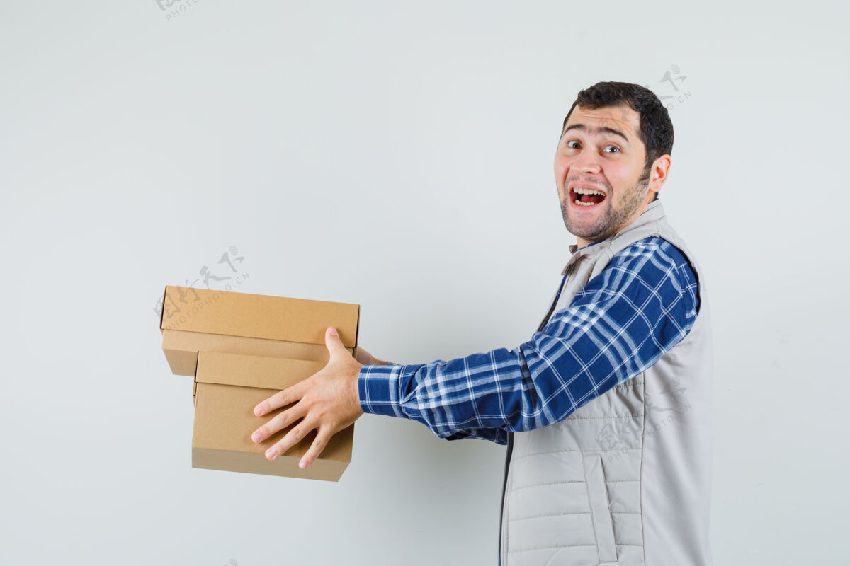 正面年轻的男性给一个穿着衬衫 夹克 看起来很快乐的人盒子 正面视图自信孩子夹克
