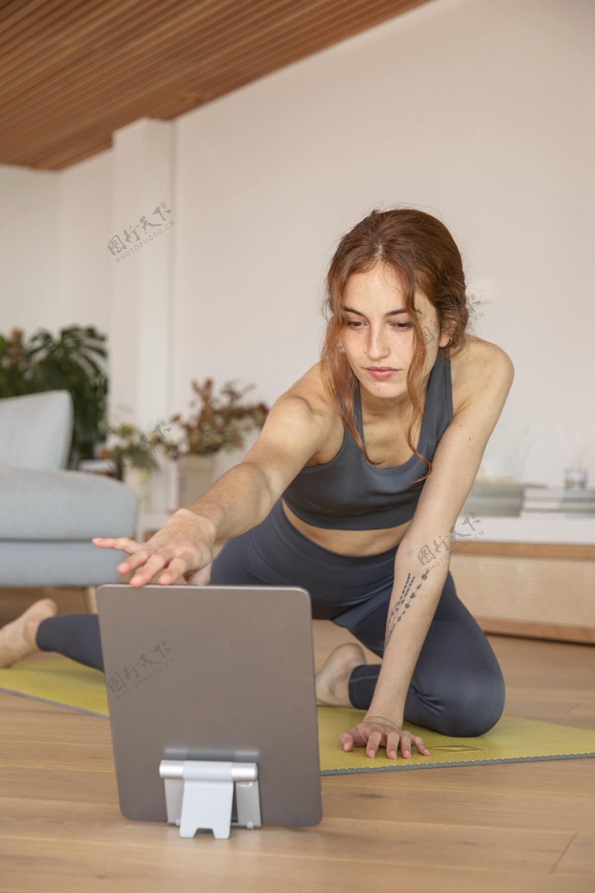 平板电脑女人在家做健身垫设备练习年轻人