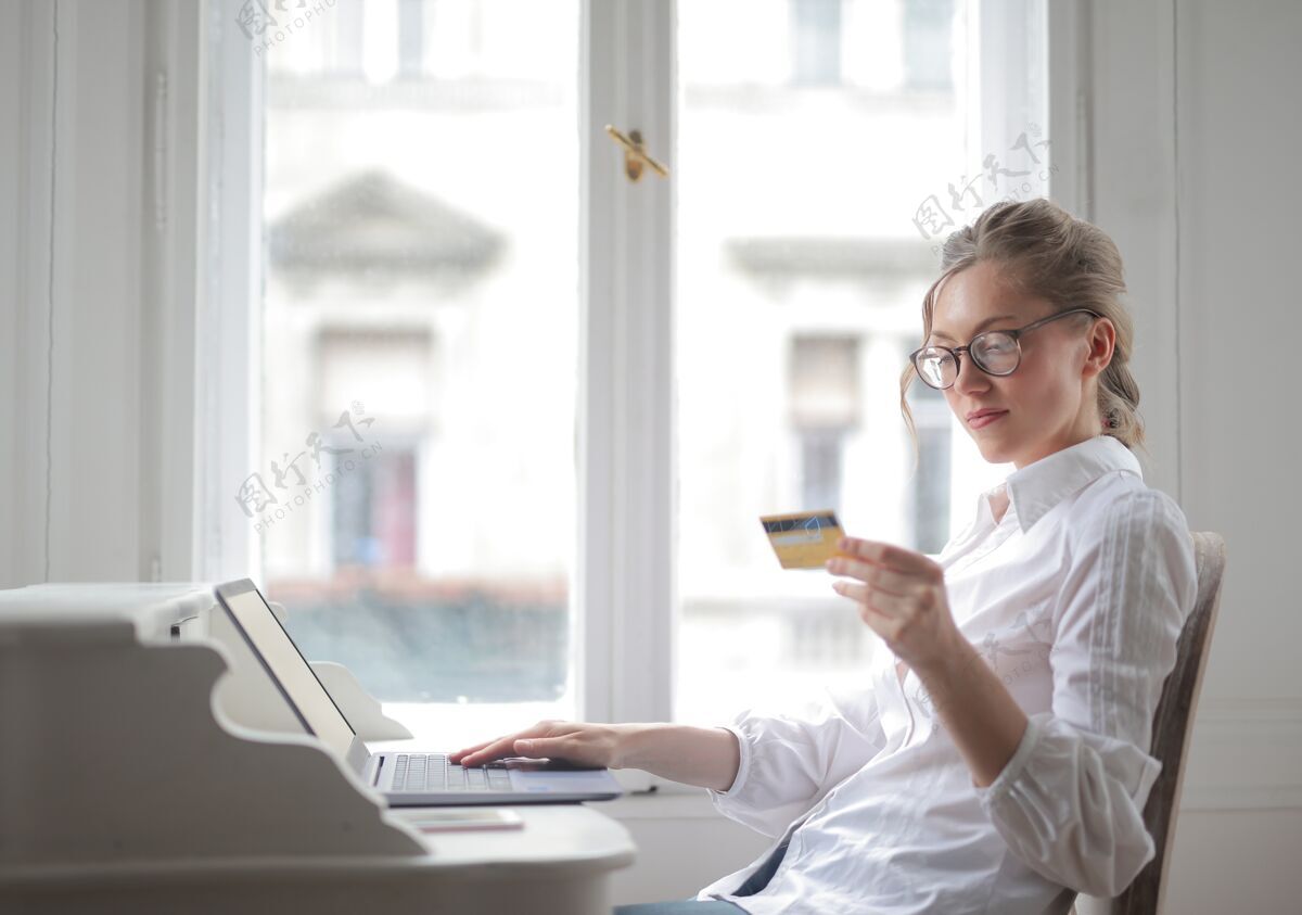 美女一个穿着白衬衫的漂亮女人用笔记本电脑看卡片的特写镜头成人专业女性