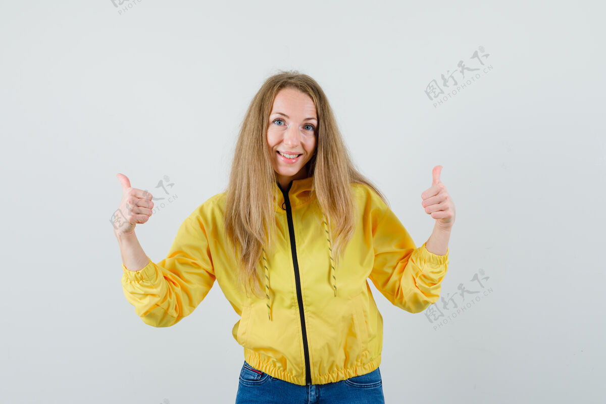 时尚身穿黄色棒球服和蓝色牛仔裤的年轻女子向上竖起大拇指 看上去很乐观 俯视前方美女拇指牛仔裤