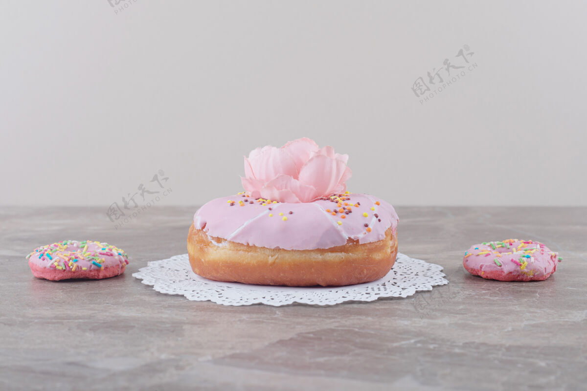 鲜花小甜甜圈旁边的一个大甜甜圈上装饰着一朵花大理石甜点美味糕点