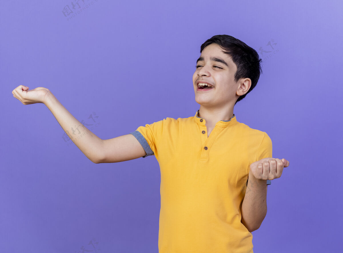 人快乐的小男孩看着一边伸出双手孤立在紫色的墙上年轻人衣服人