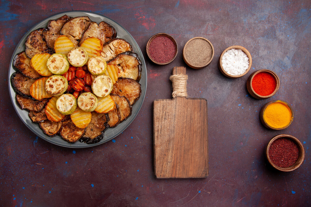 食物顶视图烤蔬菜土豆和茄子与不同的调味品在黑暗的空间烘焙核桃调味品