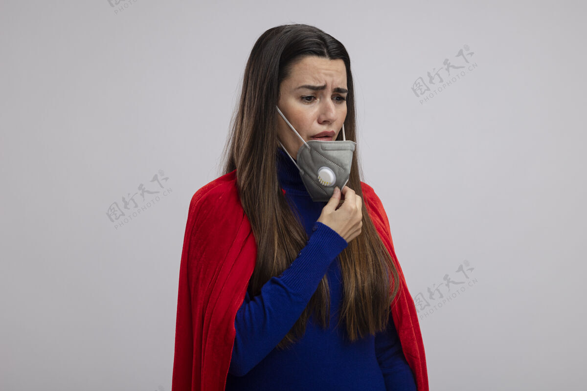 悲伤悲伤的年轻超级英雄女孩戴着一个医用面具 在白色的背景下被隔离面具医疗超级英雄