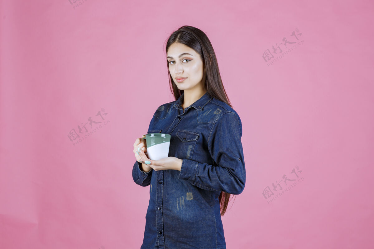 美食年轻女子拿着一个白绿色的咖啡杯 闻着女性模特姿势