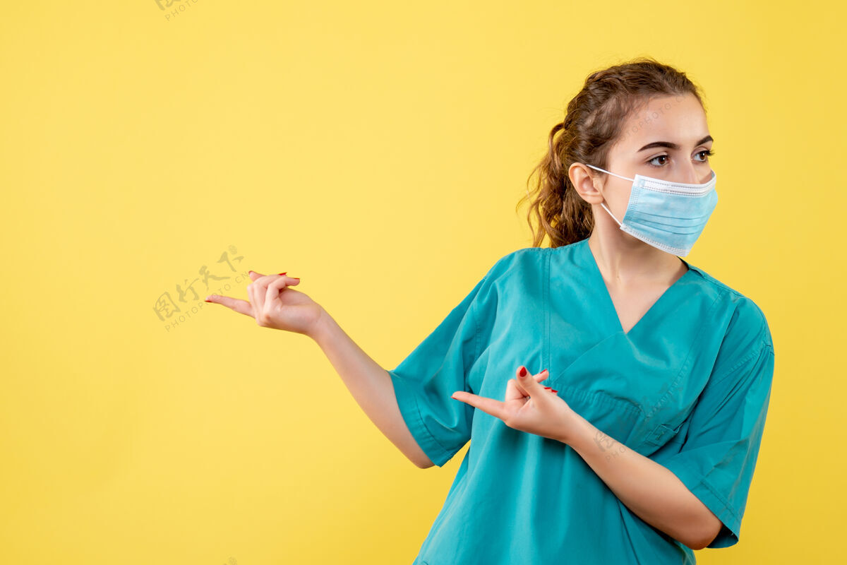肖像正面图女医生穿着医用衬衫和无菌口罩 黄色办公桌上有健康病毒制服颜色covid-医疗人女医生