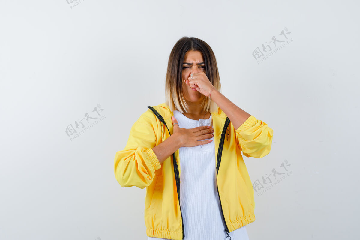 护理年轻女孩紧握拳头 打着喷嚏 穿着白色t恤 黄色夹克 看上去精疲力尽 前视图皮肤头发肖像