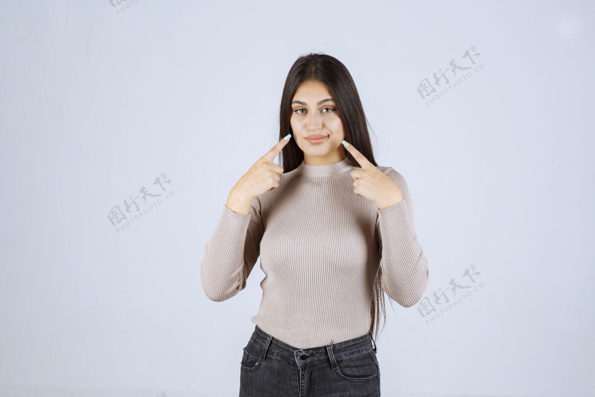女性穿灰色衬衫的女孩指着她的嘴聪明人体模特年轻