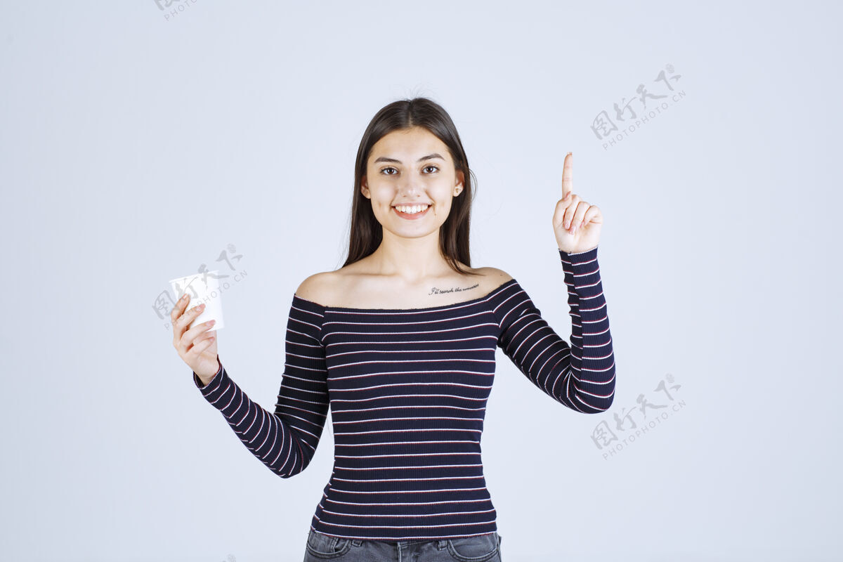 人体模特穿着条纹衬衫的女孩拿着一个塑料咖啡杯 介绍它是一种产品女人销售女售货员