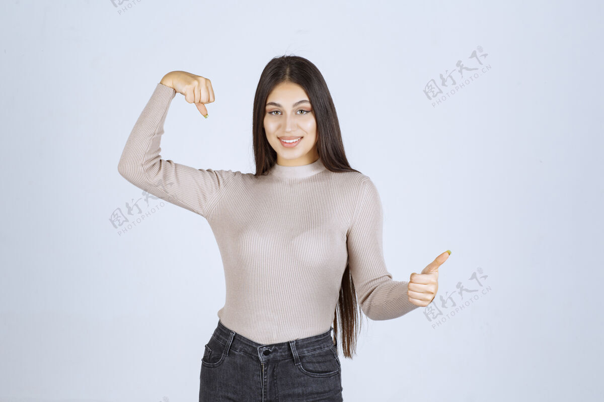 服装穿灰色衬衫的女孩展示她的拳头和肌肉人类力量工人