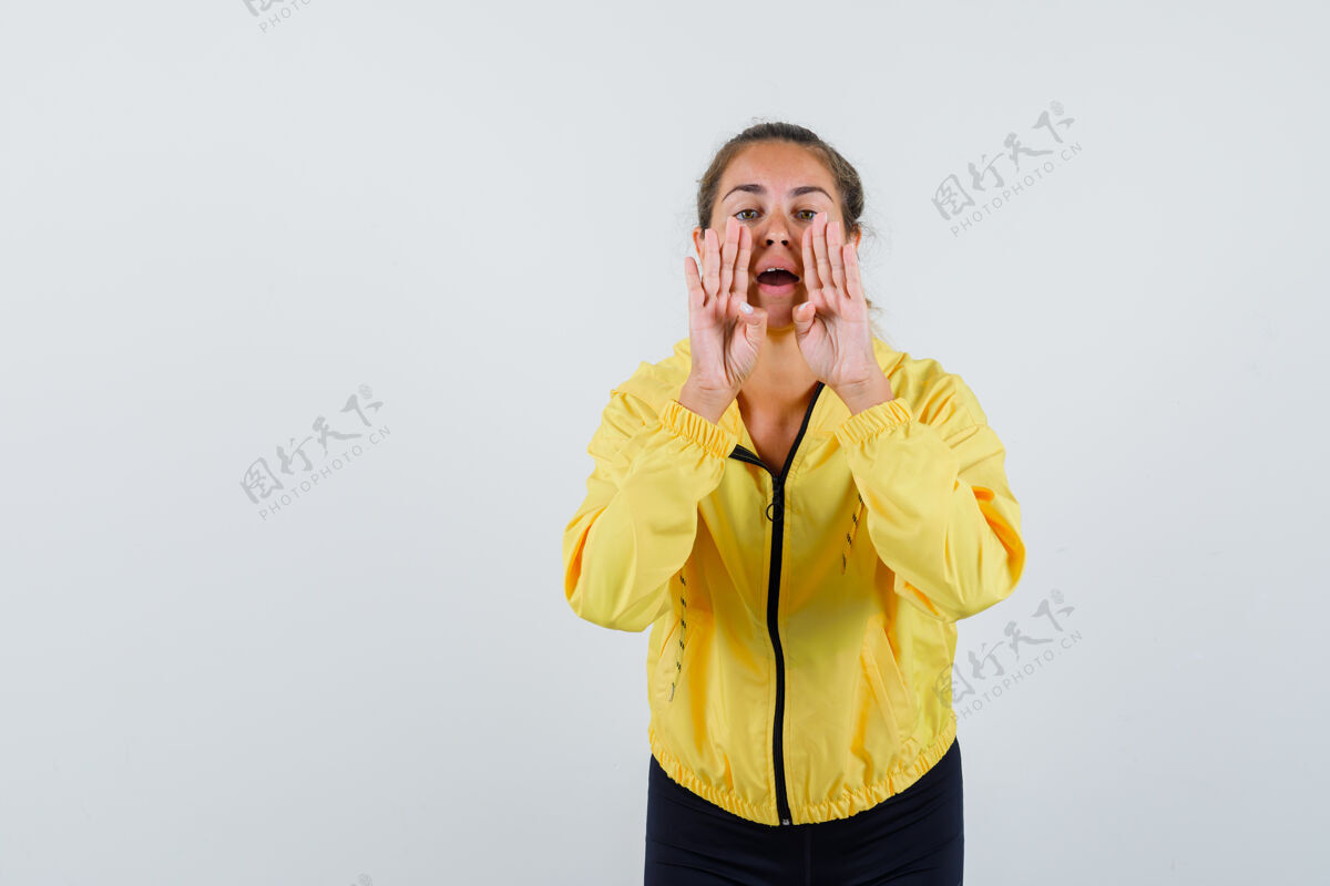 成人一个金发女人 手举在嘴边 叫着一个穿着黄色棒球服和黑色裤子的人 看起来很开心前面呼叫近