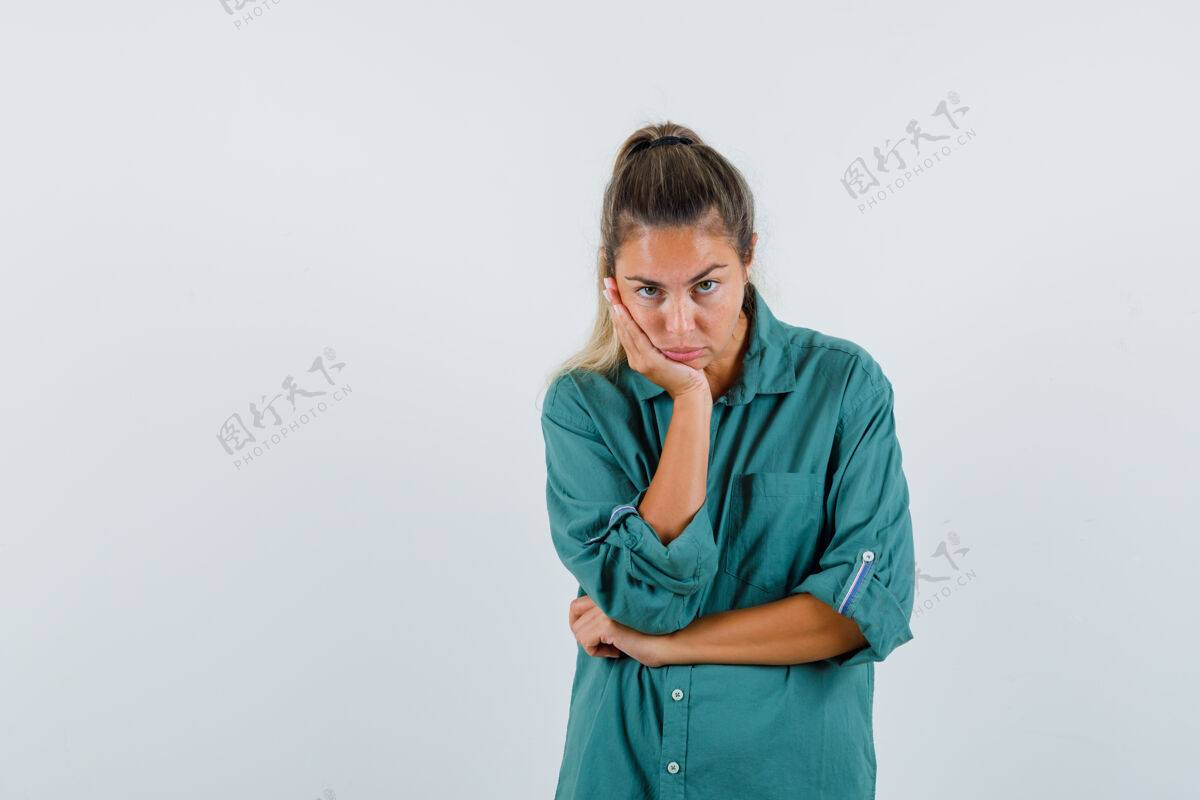 女人一个穿着蓝色衬衫的年轻女子一边看着摄像机 一边靠在胳膊肘旁 看上去很无聊肖像欢呼现代
