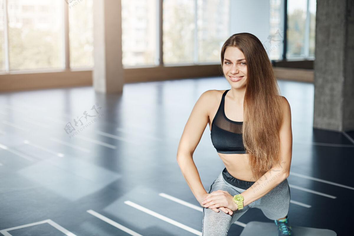 女士一大早在空荡荡的健身房里伸展双腿的美丽健康的成年女士的画像力量健身房成人