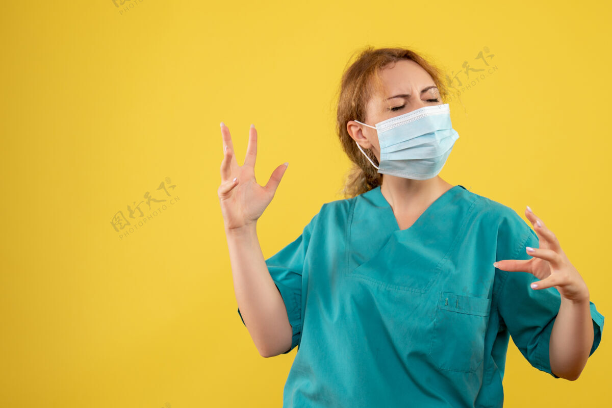 正面黄墙上年轻女医生穿着医疗服 戴着口罩的正面图人医疗人