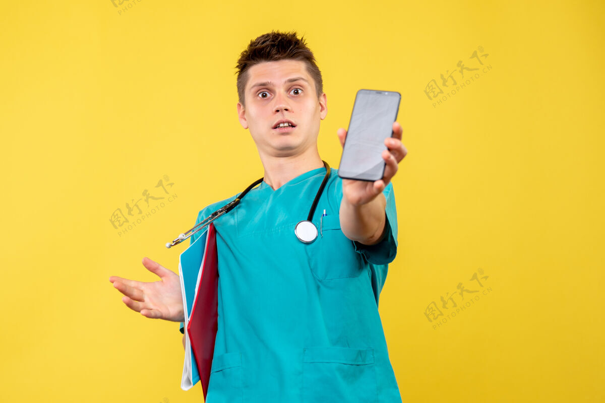 医生身穿医疗服的男医生的正面图 黄色墙上有电话和便条情绪医疗人