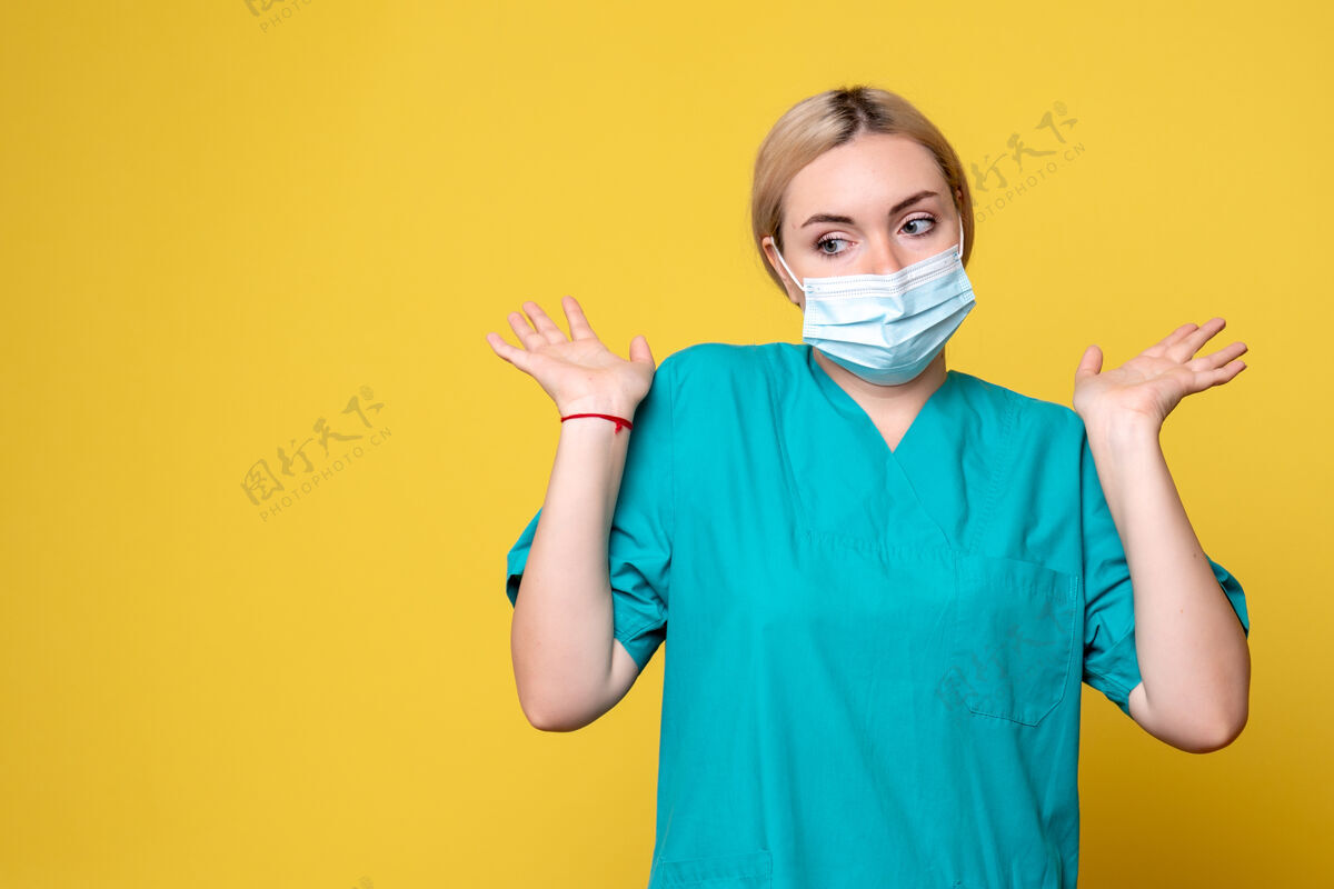 正面黄墙上年轻女医生穿着医用衬衫 戴着口罩的正面图年轻女医生表情成人