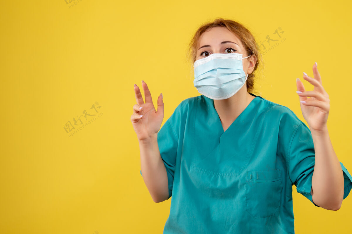 封面黄色墙上戴着无菌防护口罩的女医生的正视图女医生正面肖像
