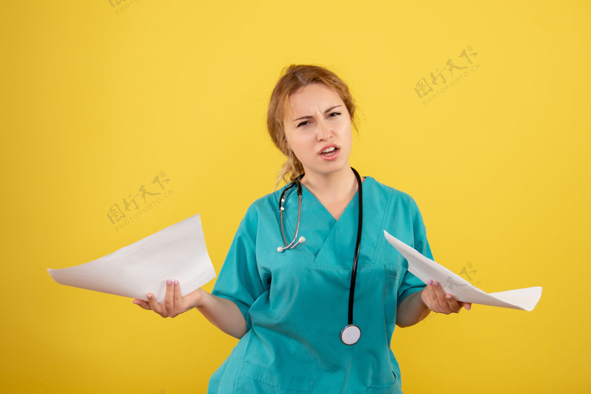 医生黄色墙壁上穿着医疗服的女医生手持分析的正面图持有医药病毒