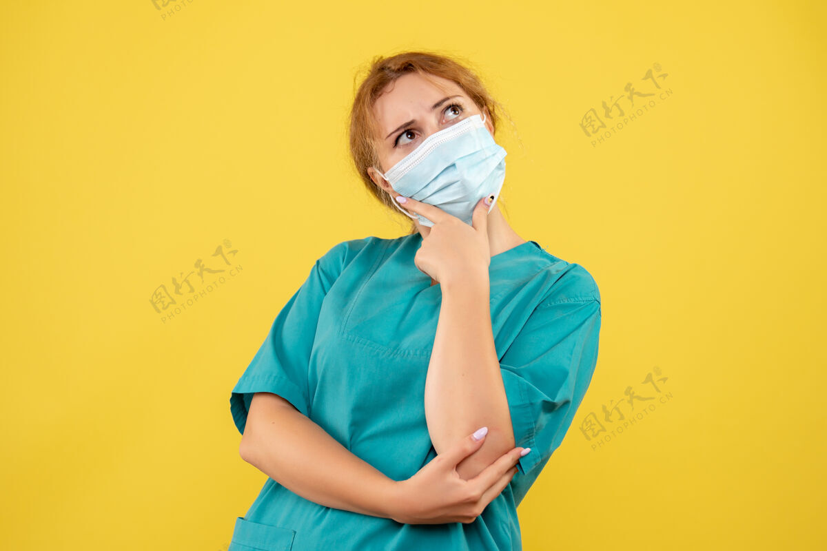 套装身着医疗服 戴着口罩的女医生在黄墙上思考面部人思维