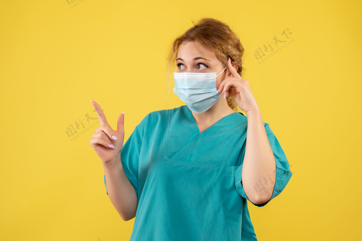 西装黄色墙壁上穿着医疗服 戴着口罩的女医生的正视图健康肖像脸