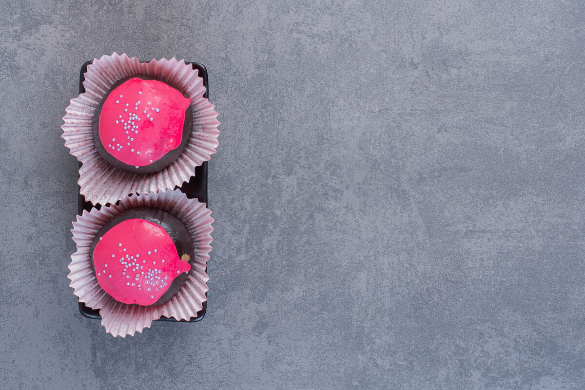 糕点黑盘子上有粉红釉的巧克力球球糖果背景