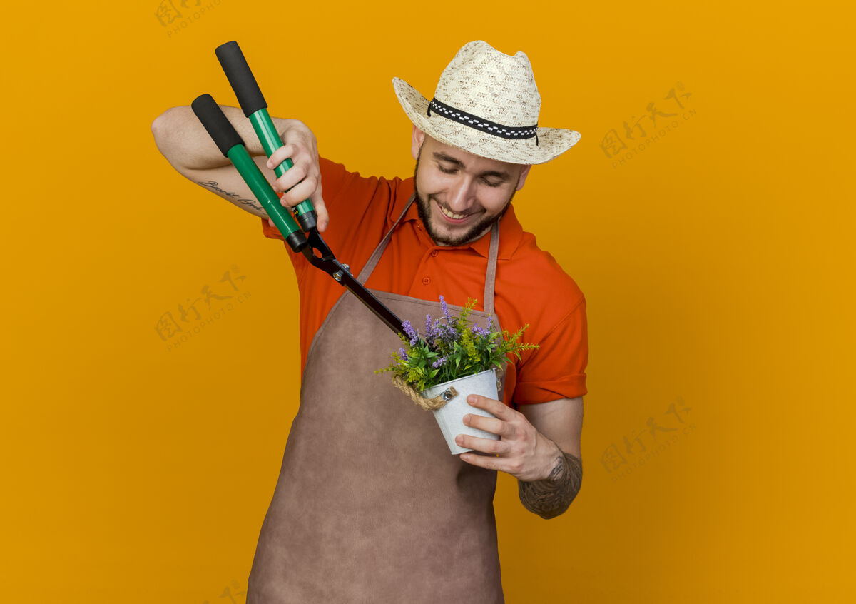 花高兴的男园丁戴着园艺帽拿着剪子假装在花盆里切花剪子园艺穿
