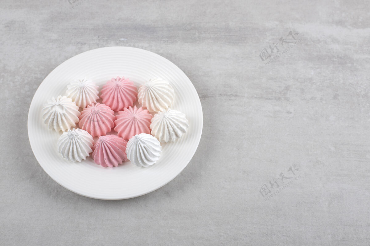 甜点粉色和白色的蛋白酥皮放在盘子里 放在大理石桌上蛋白酥皮卡路里盘子